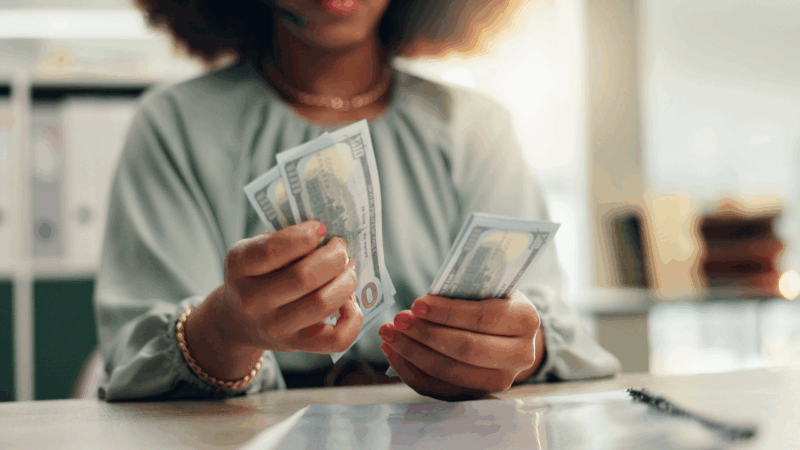 Closeup of a woman counting hundred dollar bills