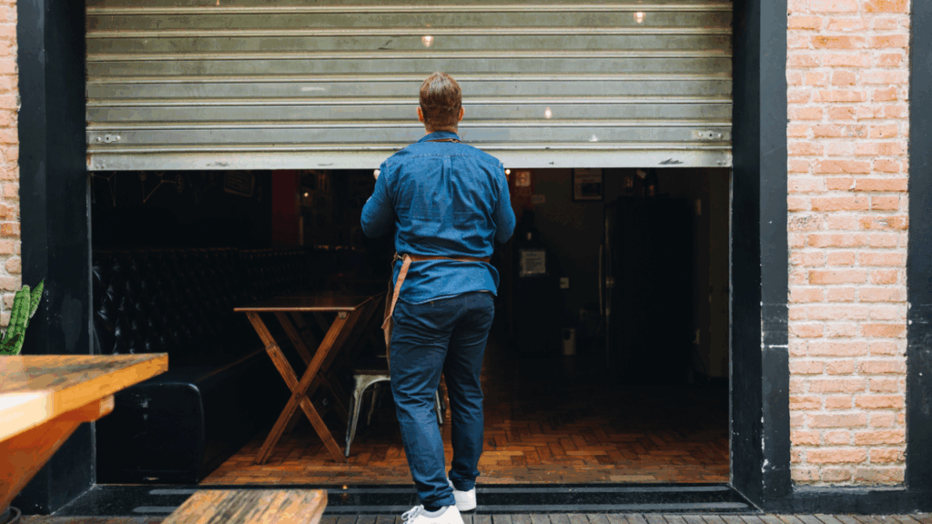 A man in an apron closing a garage door